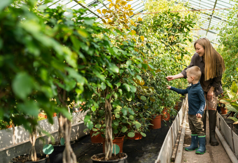 A mom teaching her son about gardening in a greenhouse