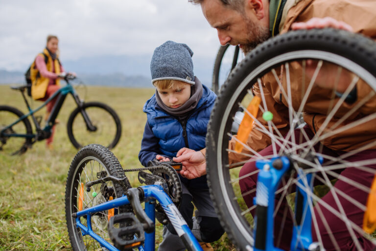 A dad teaches his son how to fix a bike